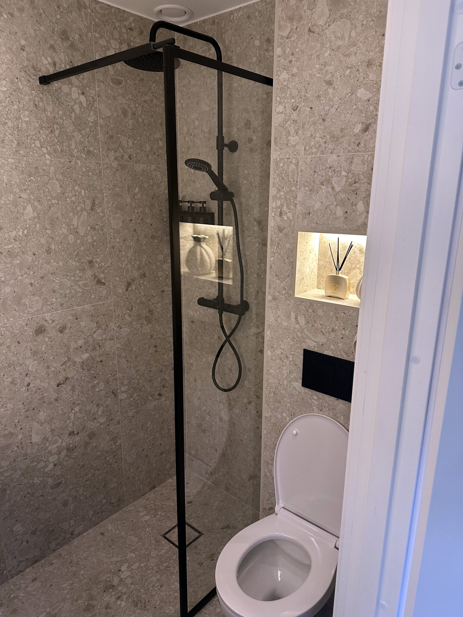 Färdigrenoverat badrum med stenytor och dusch